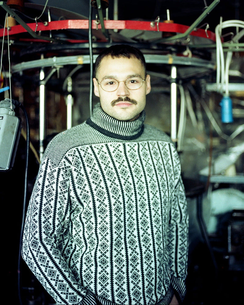 Picture of man with retro looking Norwegian jumper. Set in what looks like a factory